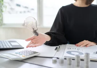 電球と資料、電卓のイメージ（節税効果のご紹介）